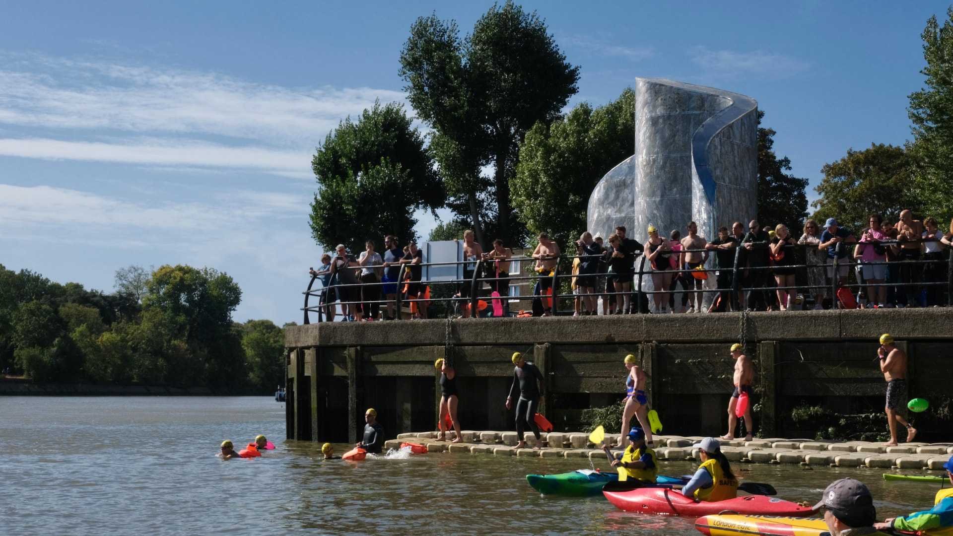 Swimmers stepping into the river at the Barnes start with safety kayaks waiting