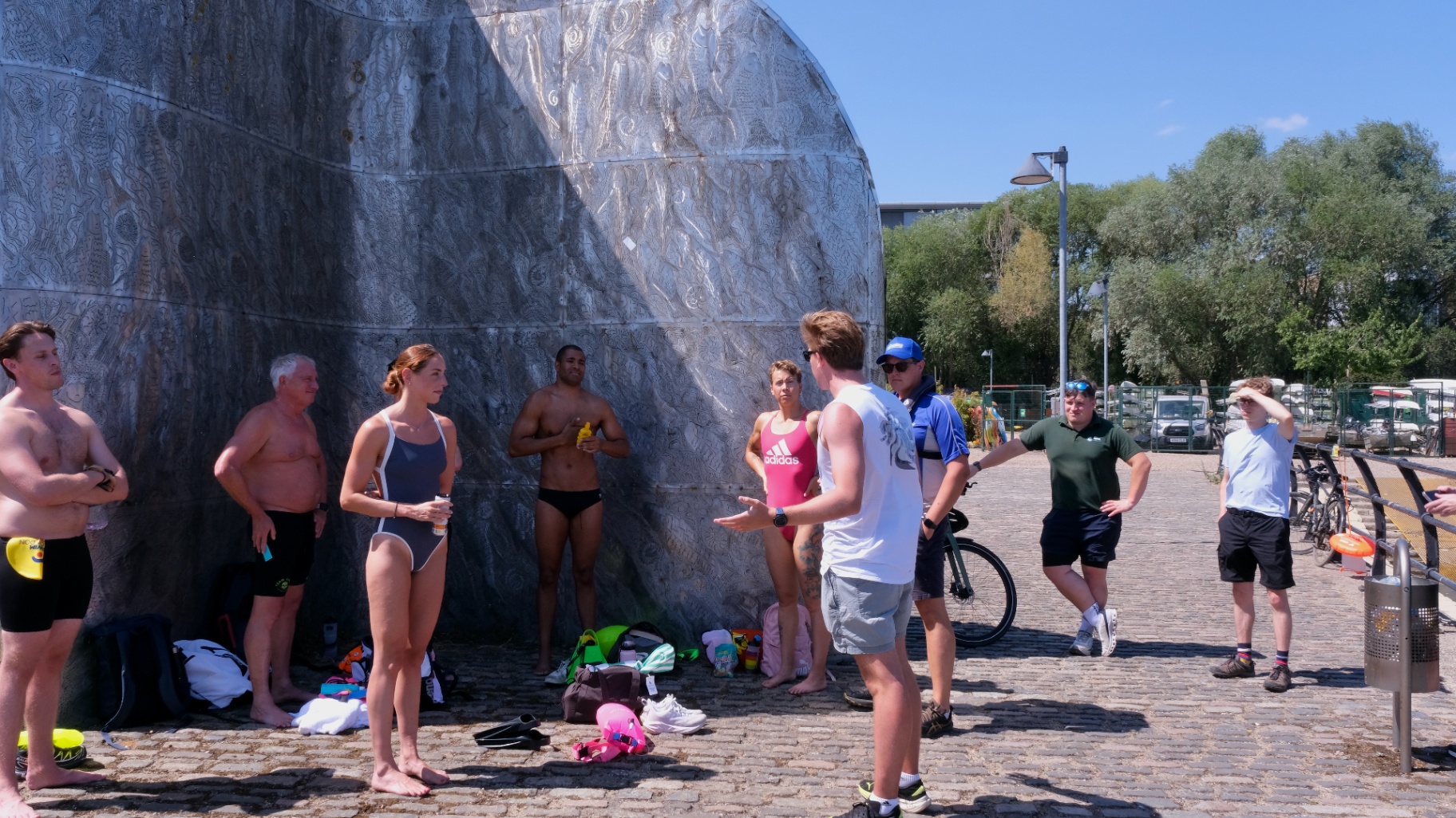 Swimmers listening to a pre-swim safety briefing on the riverside