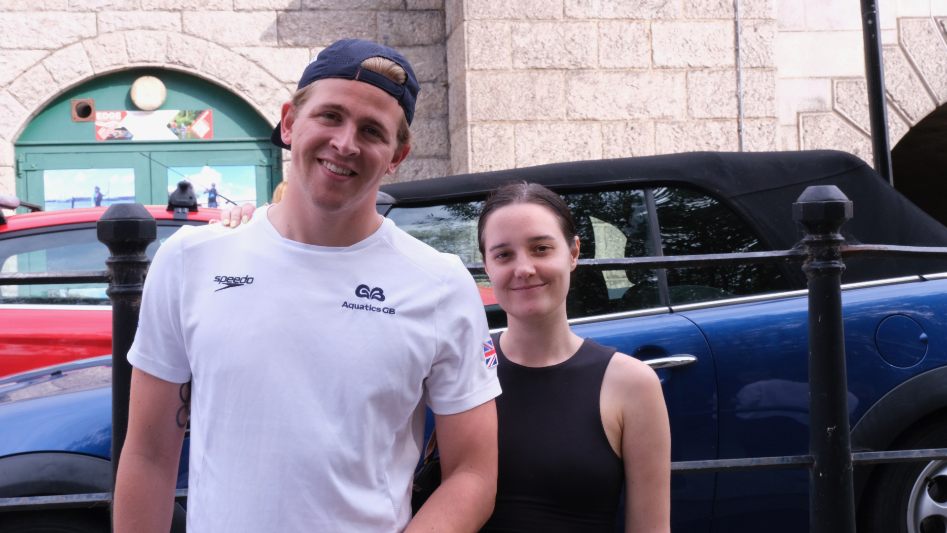Two supporters posing together in front of a stone riverside backdrop