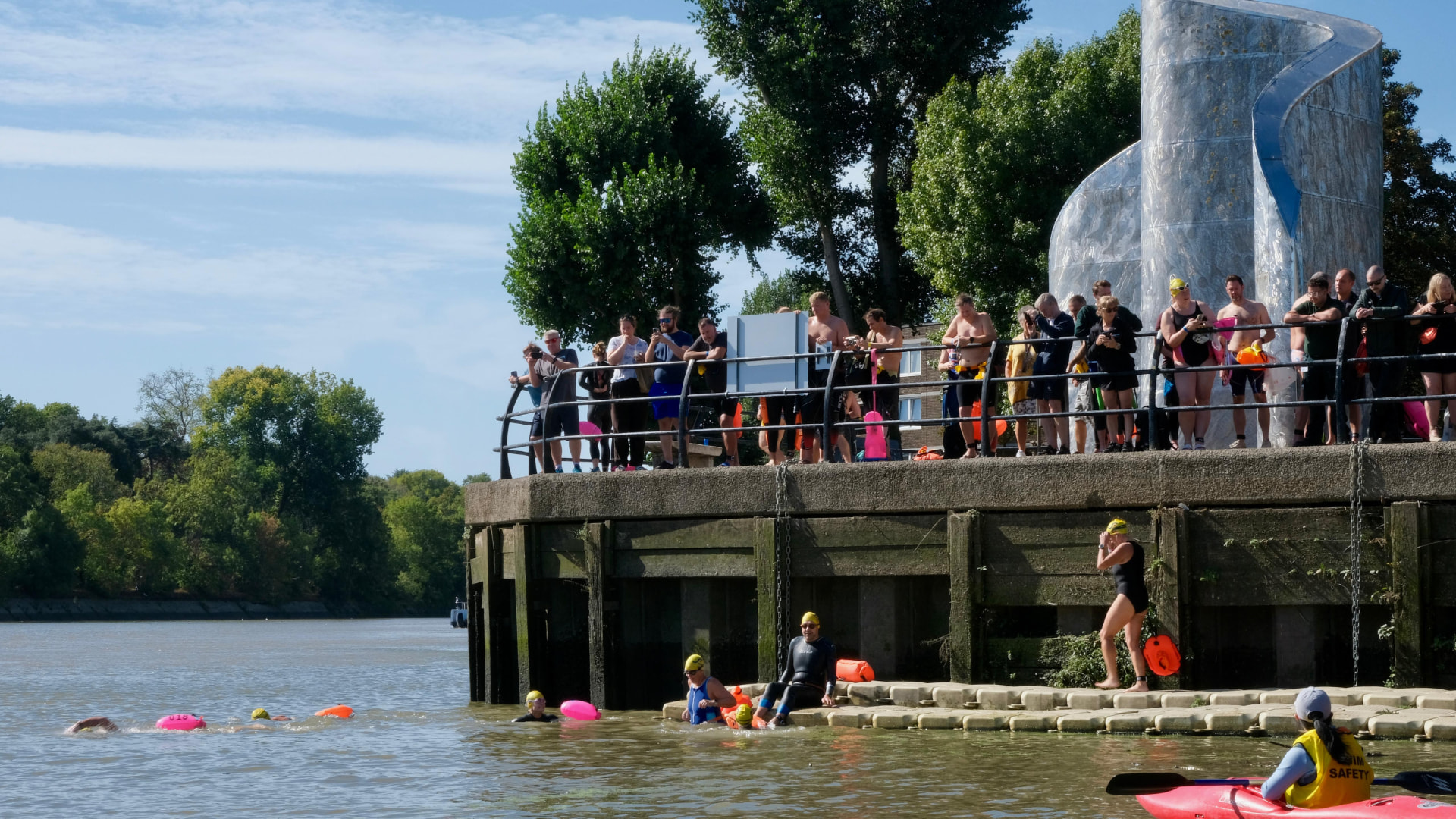 Swimmers entering the Thames from the Barnes start pontoon as supporters watch from the wall above