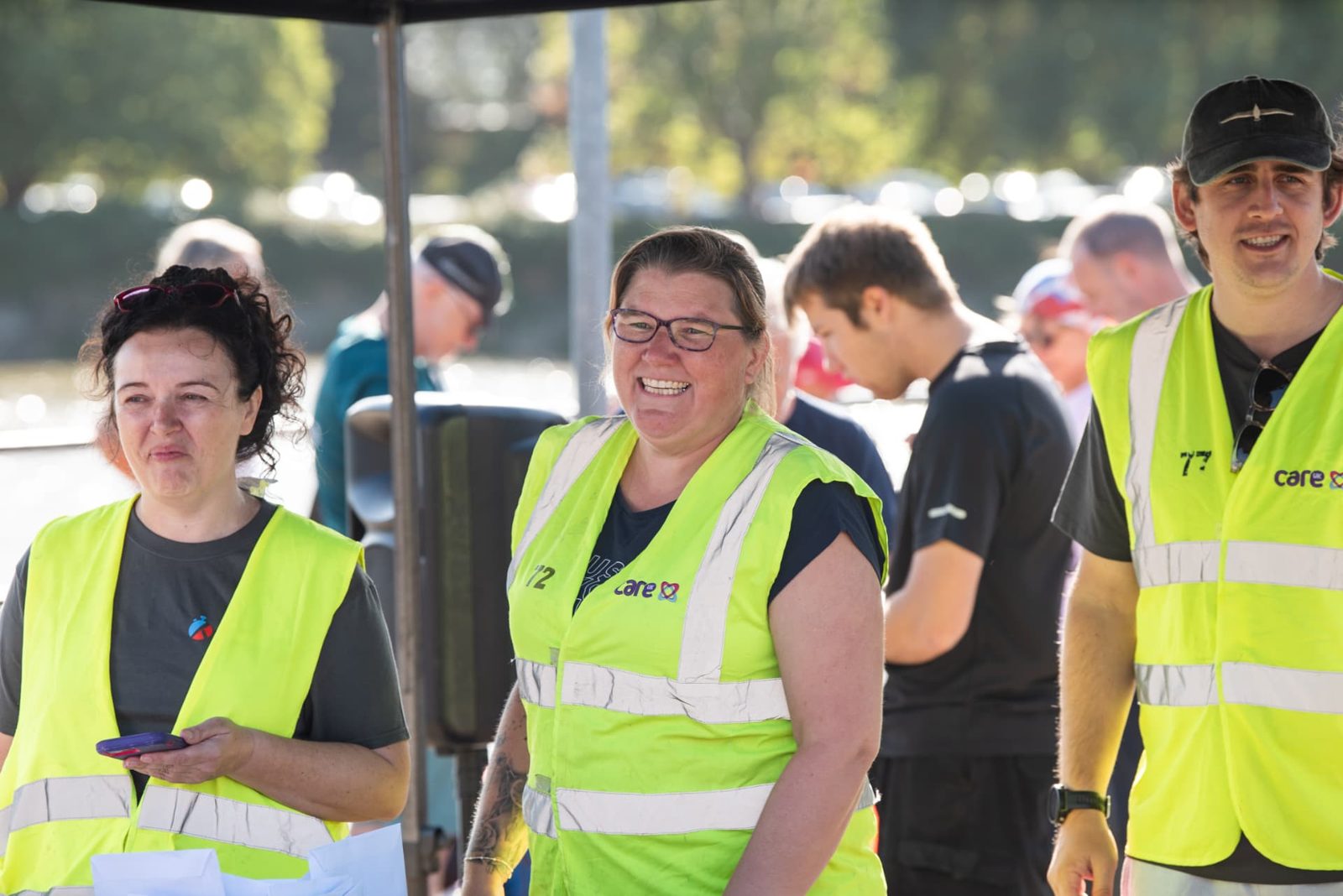 Volunteers in high-visibility vests smiling at the start area