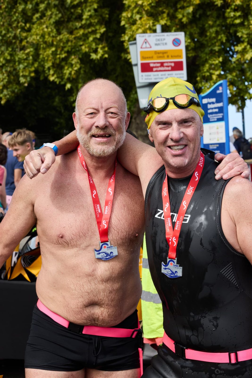 Two 10K finishers with arms around each other wearing their Swim London medals