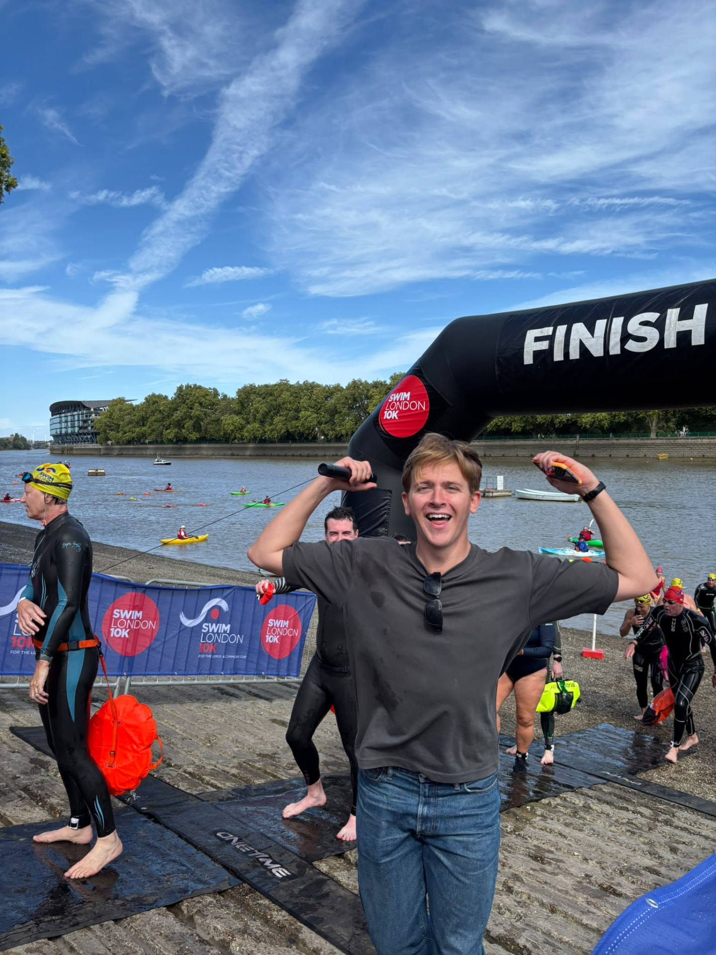 A finisher celebrating under the Swim London 10K finish arch at Putney